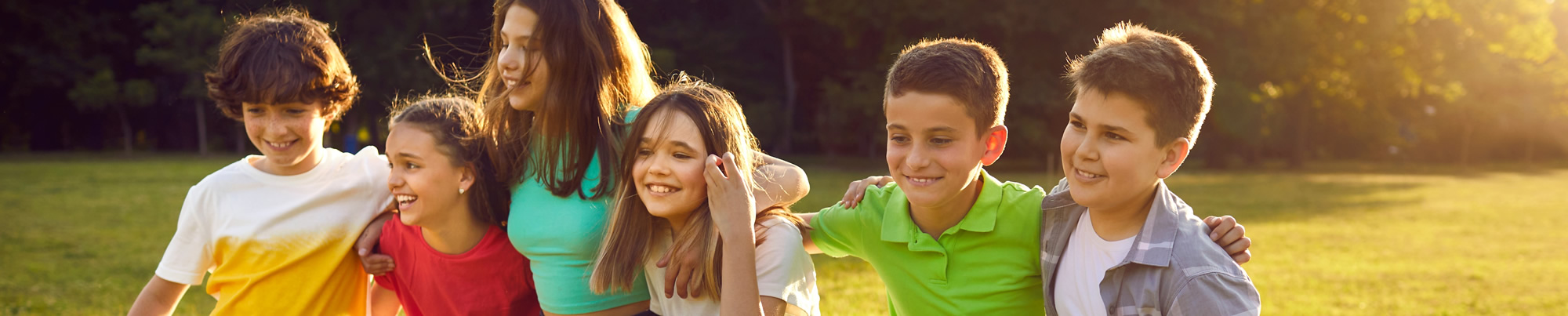 Gruppe von Kindern, die auf grünem Feld laufen, umarmt, lächeln und Spaß haben.